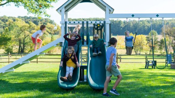 Children are playing on a vinyl swing set from King Swings.