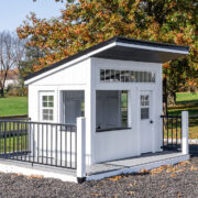 A white playhouse nestled in a rubber mulch bed