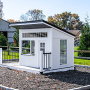 A white playhouse nestled in a bed of rubber mulch