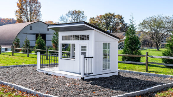 A white playhouse nestled in a bed of rubber mulch