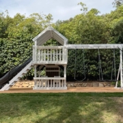 A white swing set with gray slides in backyard