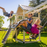 Children are swinging on a white swing set from King Swings