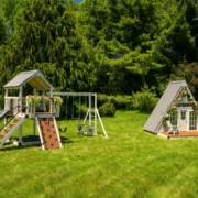 A swing set and an A frame Playhouse are sitting in a grassy field