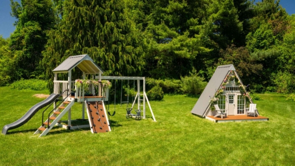 A swing set and an A frame Playhouse are sitting in a grassy field